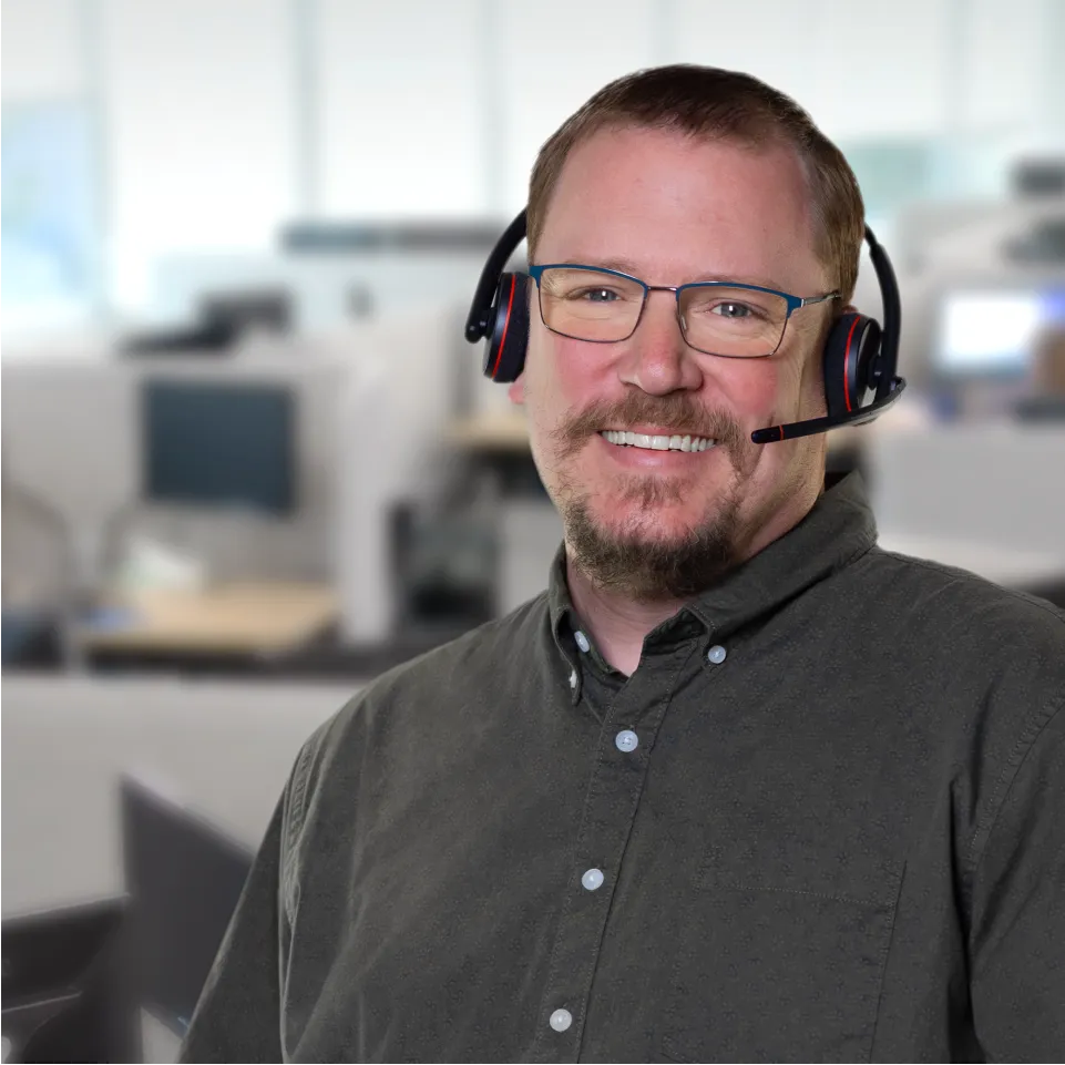 A man with a headset smiles in the workplace.