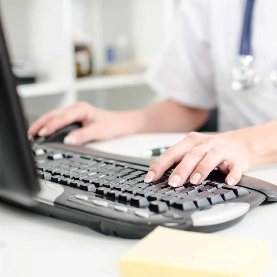 A doctor types on the computer keyboard.